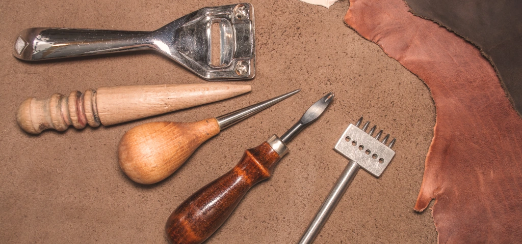 Materiales y herramientas de guarnicionero preparados para trabajar una pieza de cuero