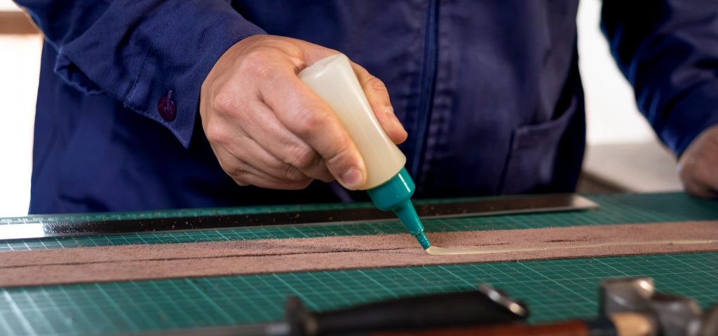 Aplicando pegamento de contacto sobre una pieza de cuero en el taller
